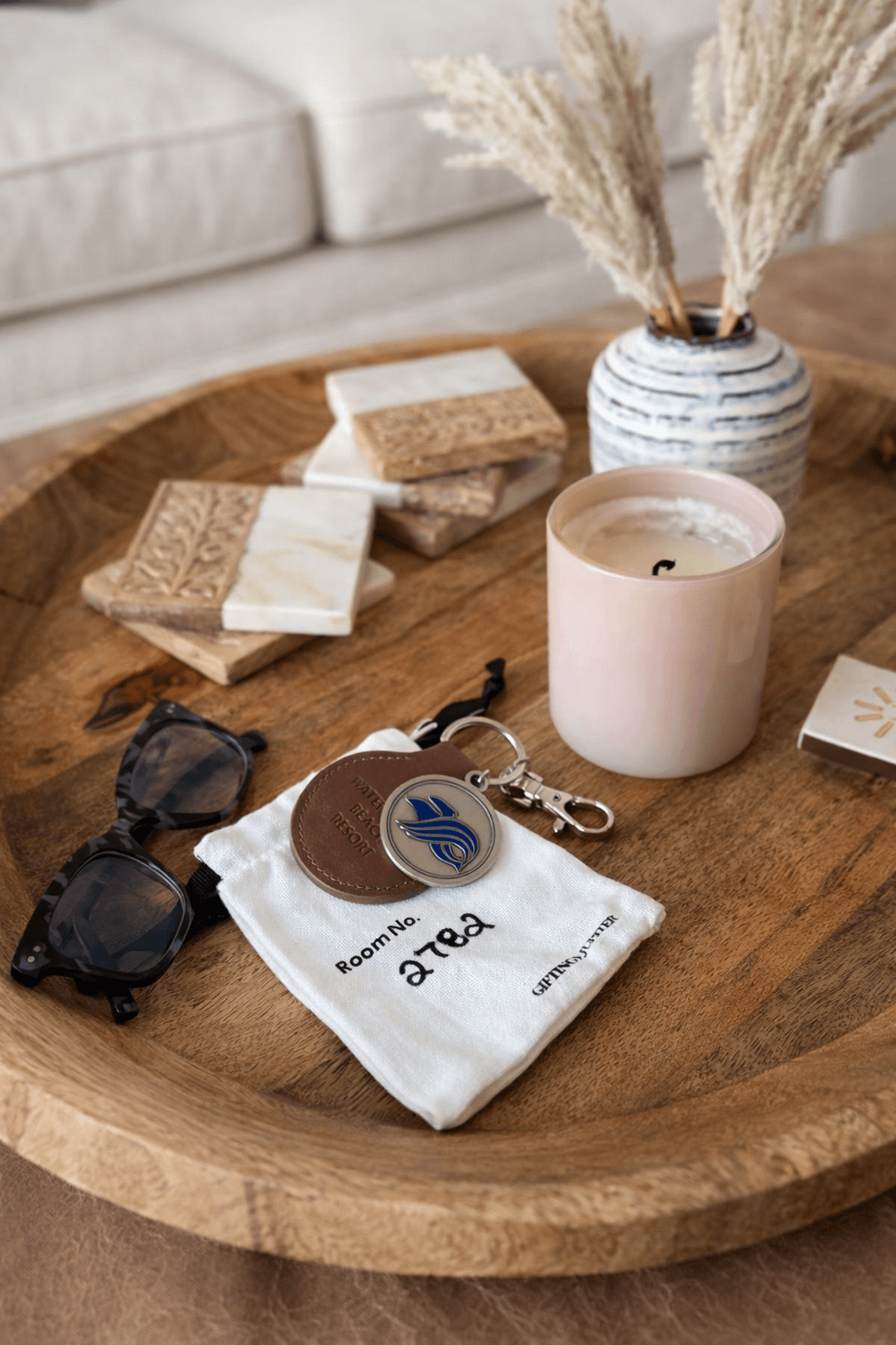 Wooden tray with candle and sunglasses.